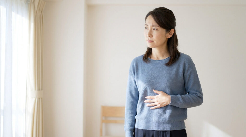 Une femme inquiète se tenant le ventre avec une expression de douleur, dans un intérieur lumineux.