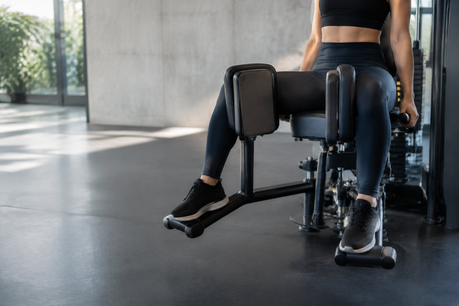 Une sportive utilisant une machine de musculation pour travailler l'ouverture des hanches et les muscles adducteurs.