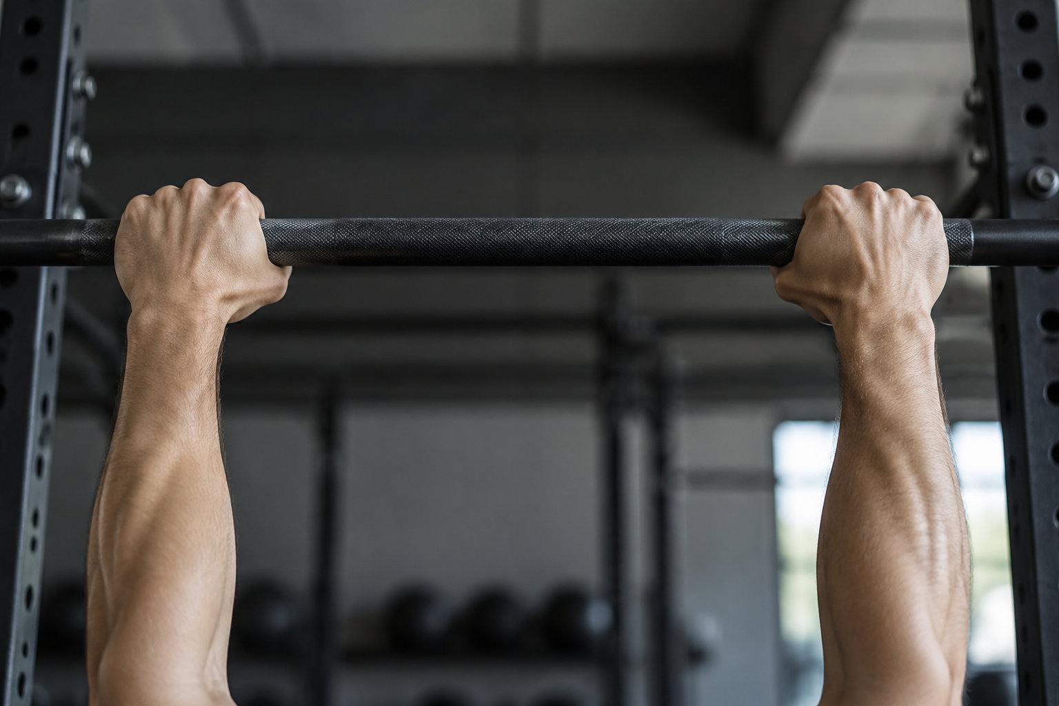 Deux mains agrippent une barre de traction dans une salle de sport.